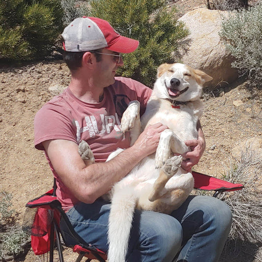 dog dad sitting in camping chair holding smiling dog on his lap