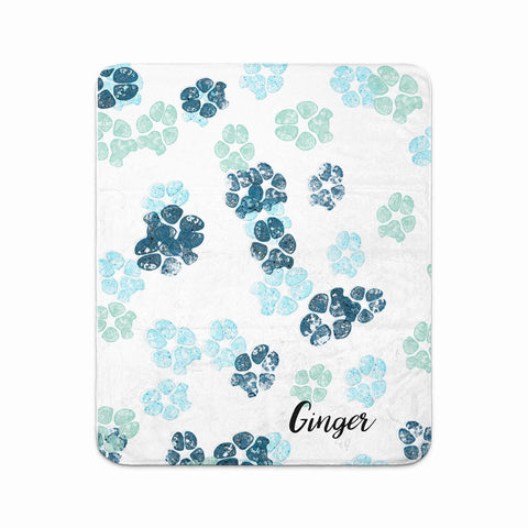 paw prints in various shades of blue scattered on blanket and personalized