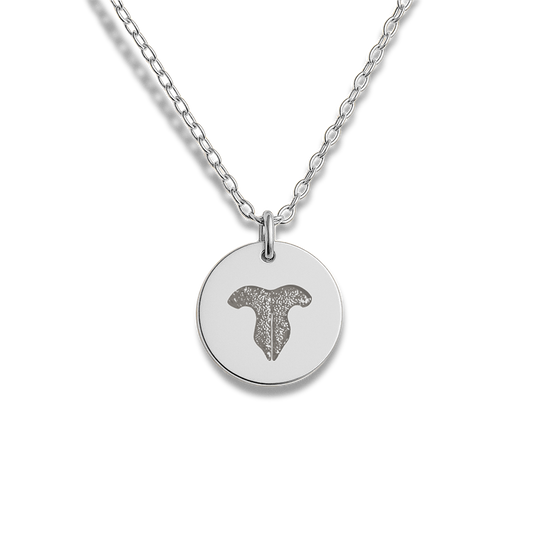 A silver necklace with a round pendant featuring a custom cat nose print.