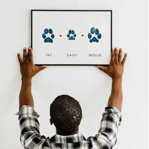 man hanging frame with three dog paw prints