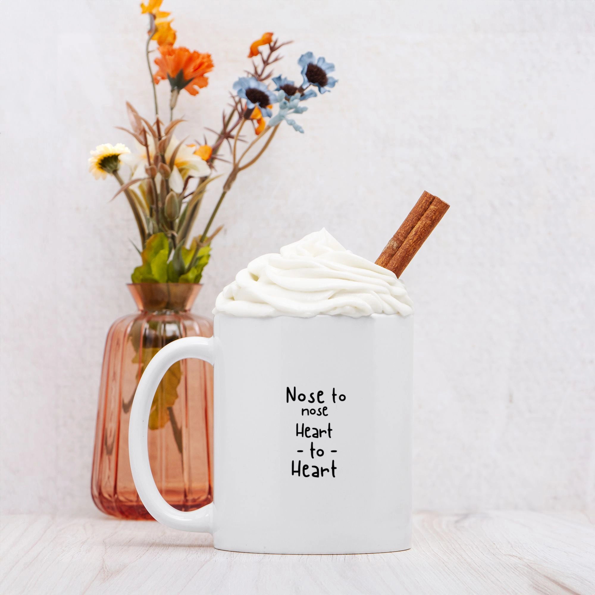 A white mug with cinnamon stick and whipped cream, bearing the text 