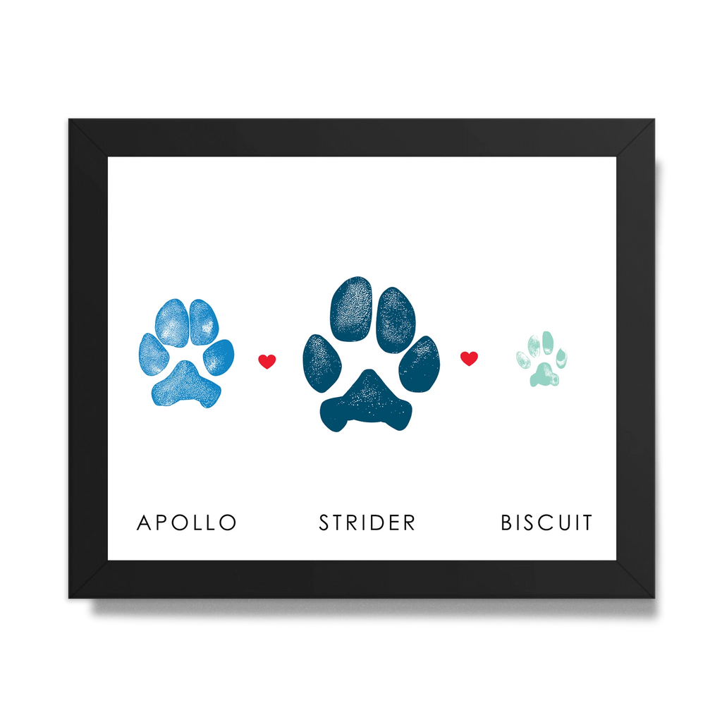 Framed art featuring two dog paw prints and one cat paw print in blue shades with small red hearts between them. Below are the names 
