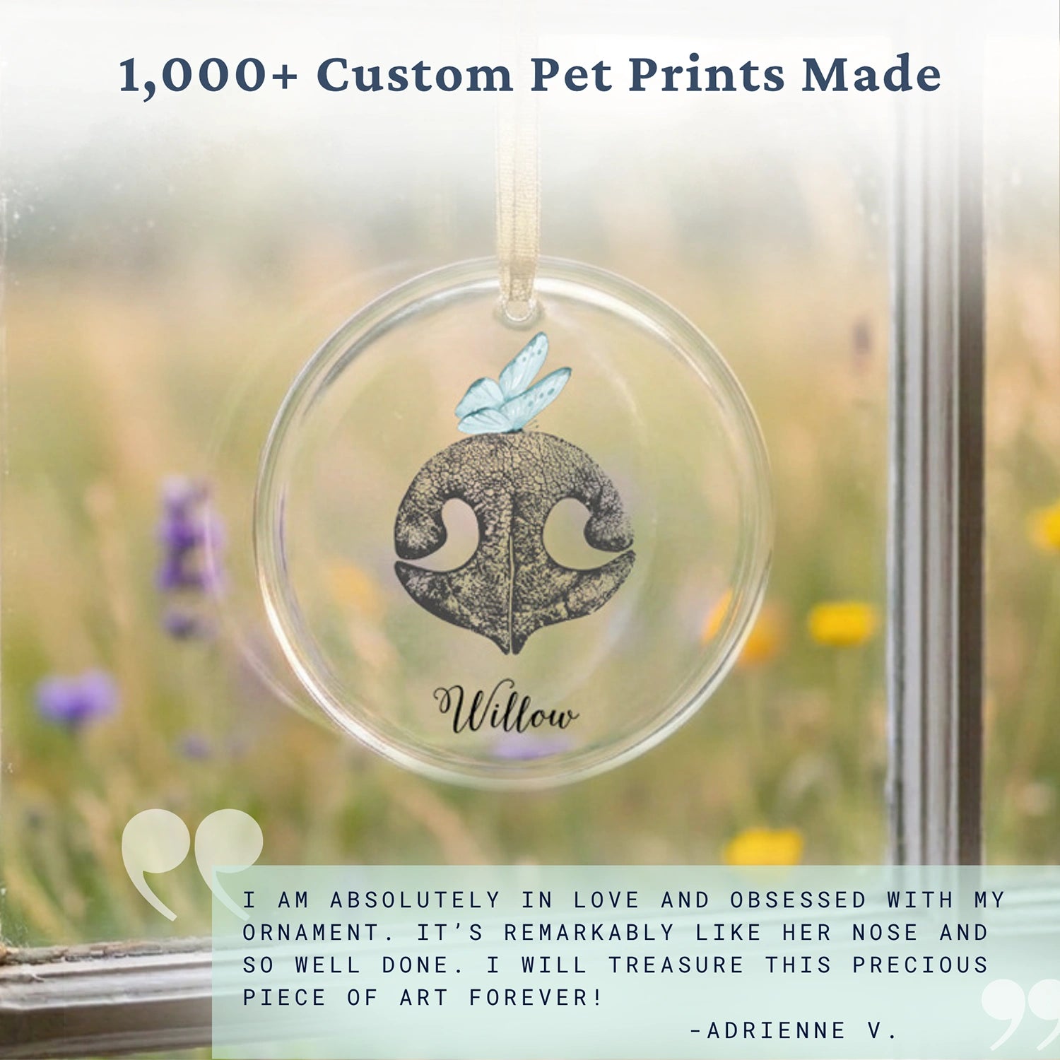A round glass ornament with a gold ribbon features an illustration of a textured, gray dog nose print and a blue butterfly. The pet name "Willlow" is inscribed below.