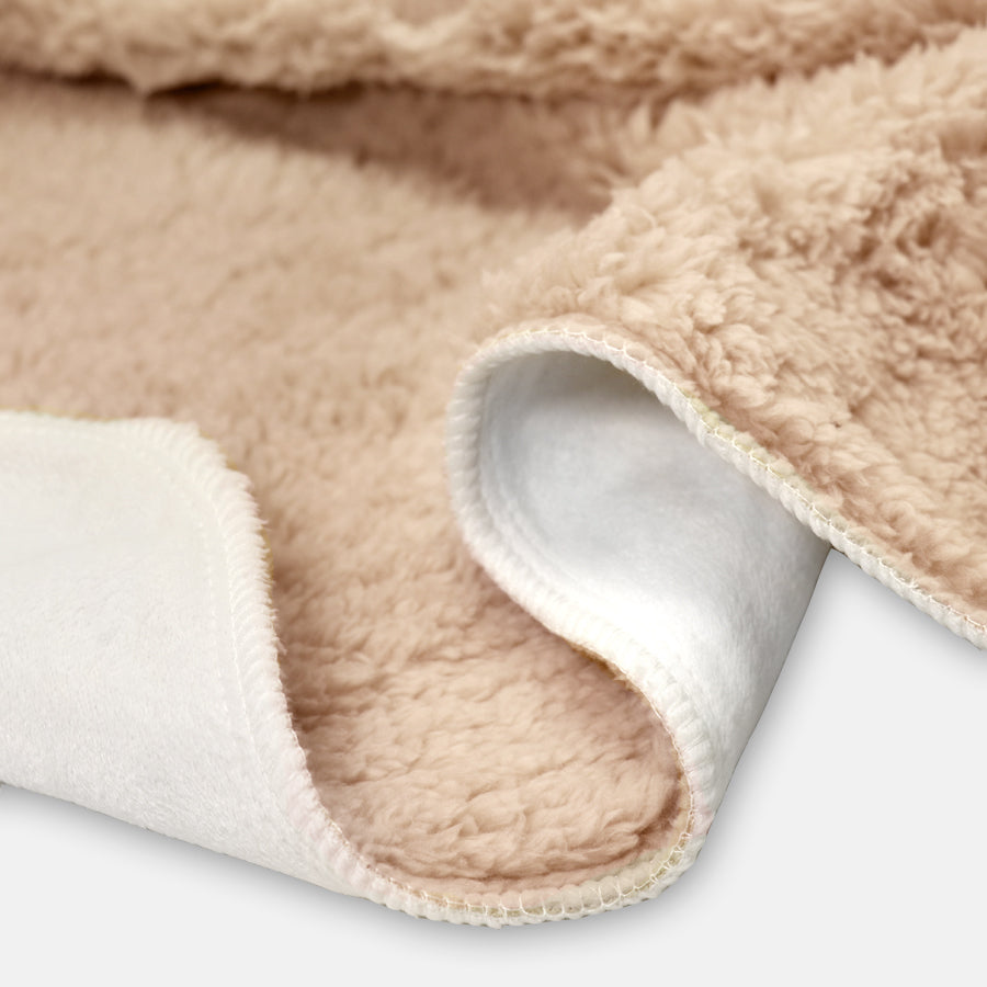 Close-up of a cozy beige sherpa fleece blanket, focusing on its plush texture and soft white lining, conveying warmth and comfort.