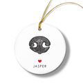 Round white ornament with a textured black dog nose print, small red heart, and the name “Jasper” beneath. Gold string for hanging attached at the top.