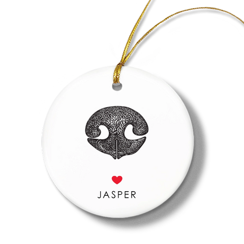 Round white ornament with a textured black dog nose print, small red heart, and the name “Jasper” beneath. Gold string for hanging attached at the top.