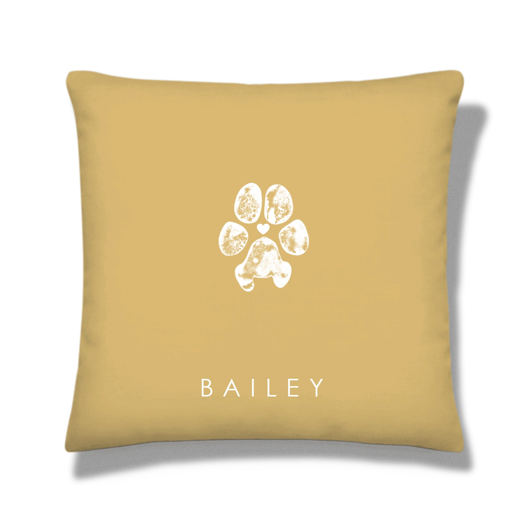 Tan pillow featuring a white dog paw print design with a small heart and in the center, above the name 