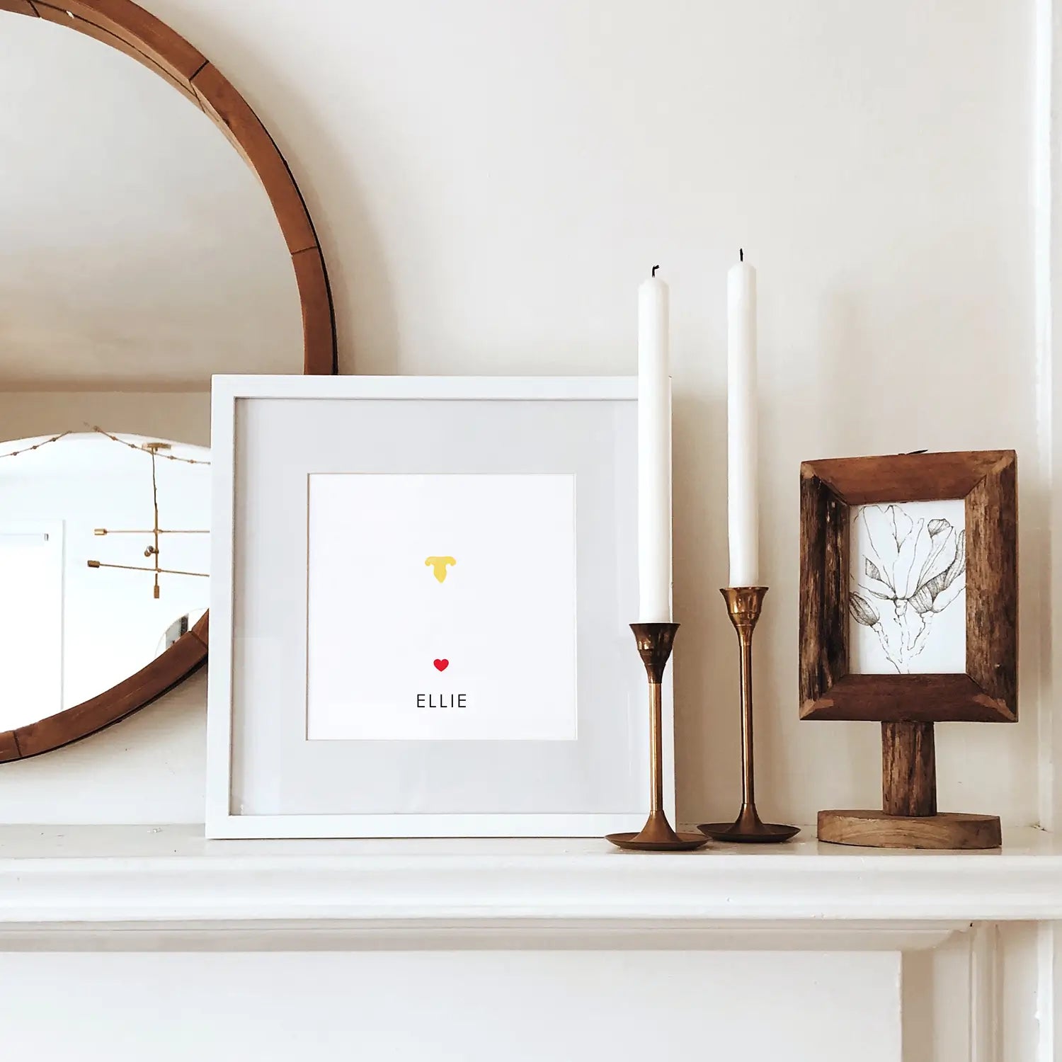 Minimalist mantel decor with a round mirror, framed art with a heart, cat's nose print and name 