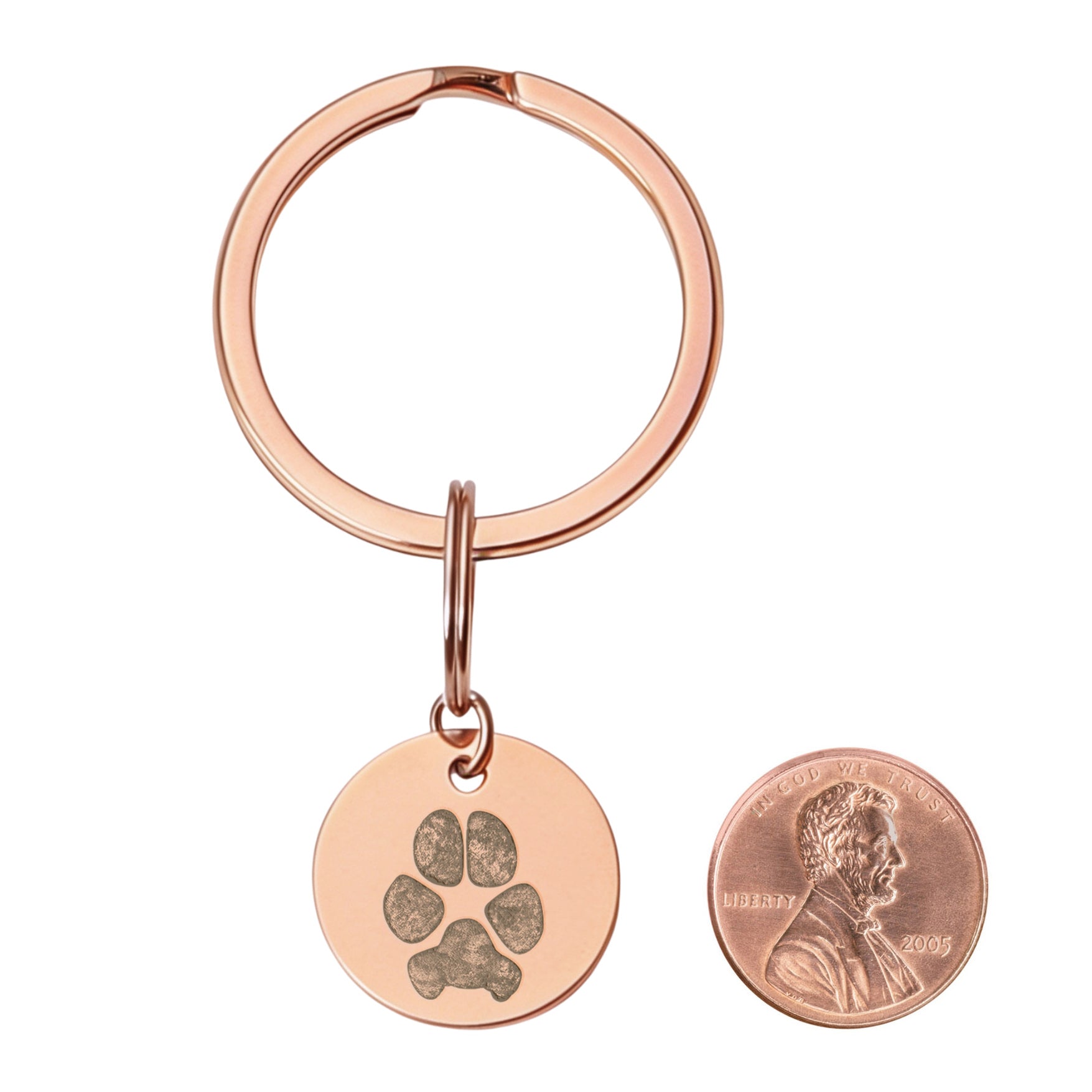 dog paw print engraved keychain next to a penny to compare size