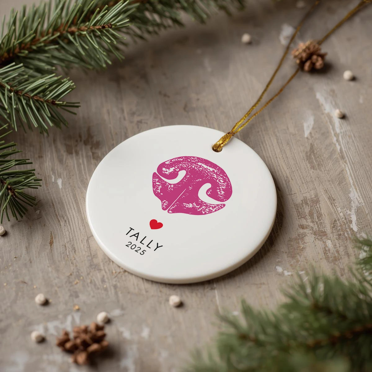 Round white ornament with a textured black dog nose print, small red heart, and the name “Jasper” beneath. Gold string for hanging attached at the top.