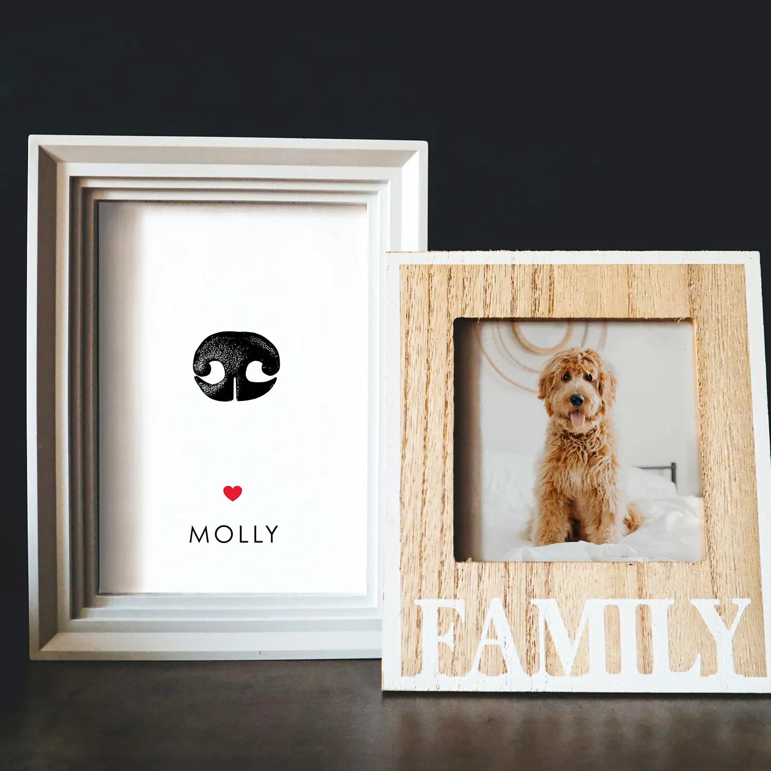 Two photo frames on a dark surface. Left: white frame with a black paw print, a red heart, and 