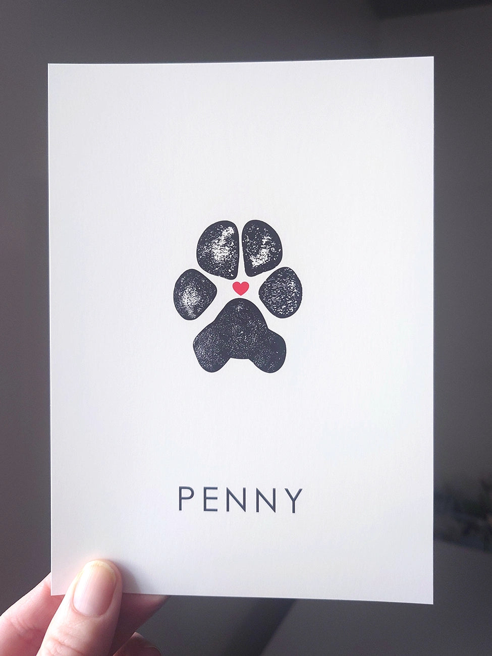 White card with a black paw print design. A small red heart is between the paw pads. 