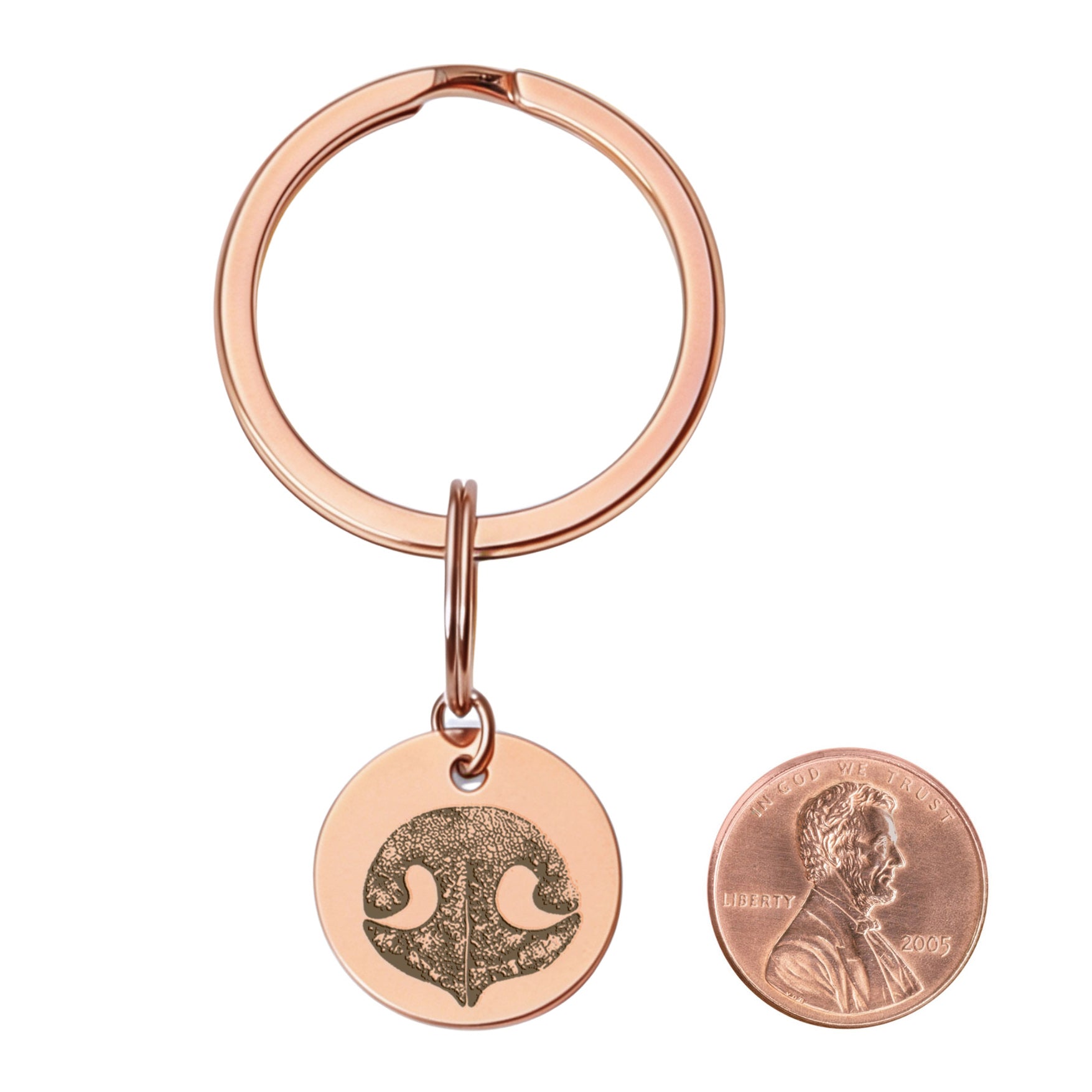 dog nose print engraved on rose gold keychain.  a penny is next to the keychain pendant for size comparison.