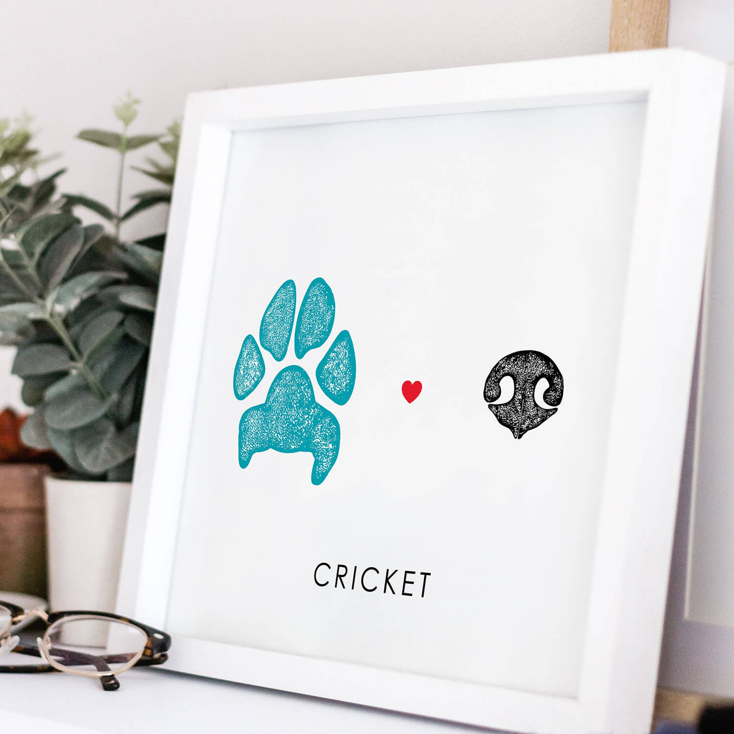 blue dog paw print and black dog nose print with heart between in white frame