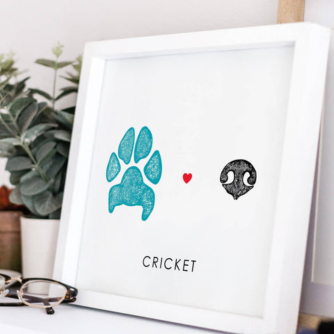 blue dog paw print and black dog nose print with heart between in white frame