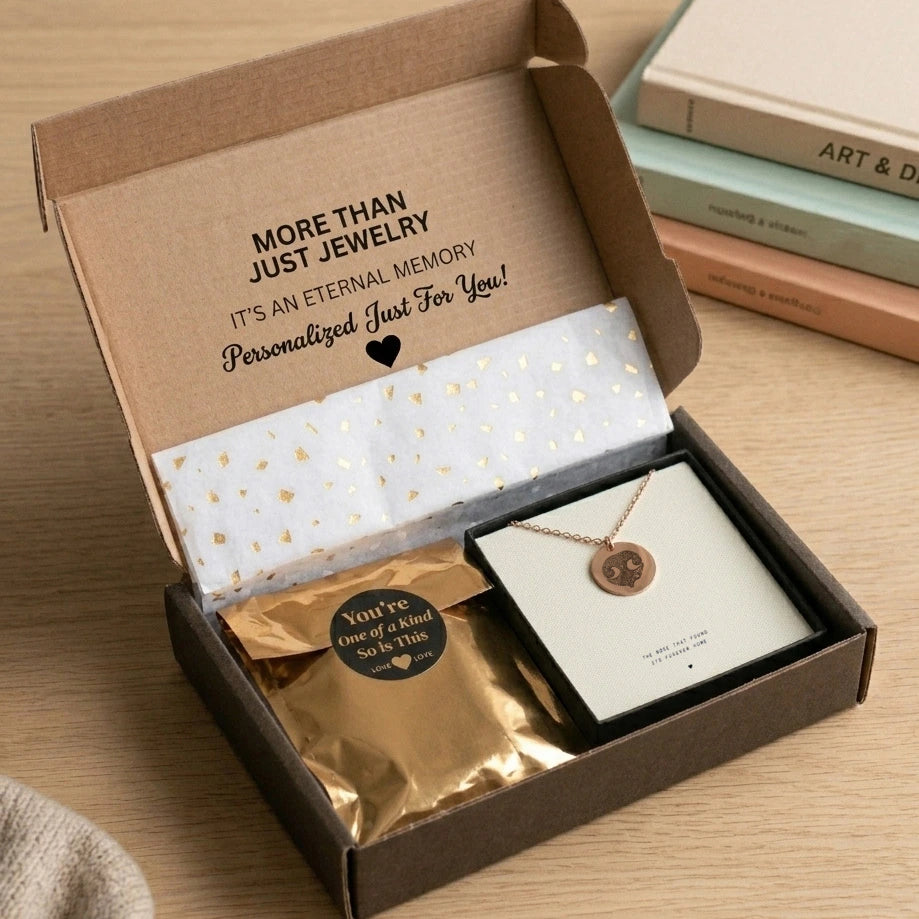 An open jewelry box lined with gold and white confetti paper contains a gold pendant cat  nose print memorial necklace and a shimmering gold package. The box lid reads, "More than just jewelry. It's an eternal memory personalized just for you!" The scene conveys a sense of luxury and personalization.