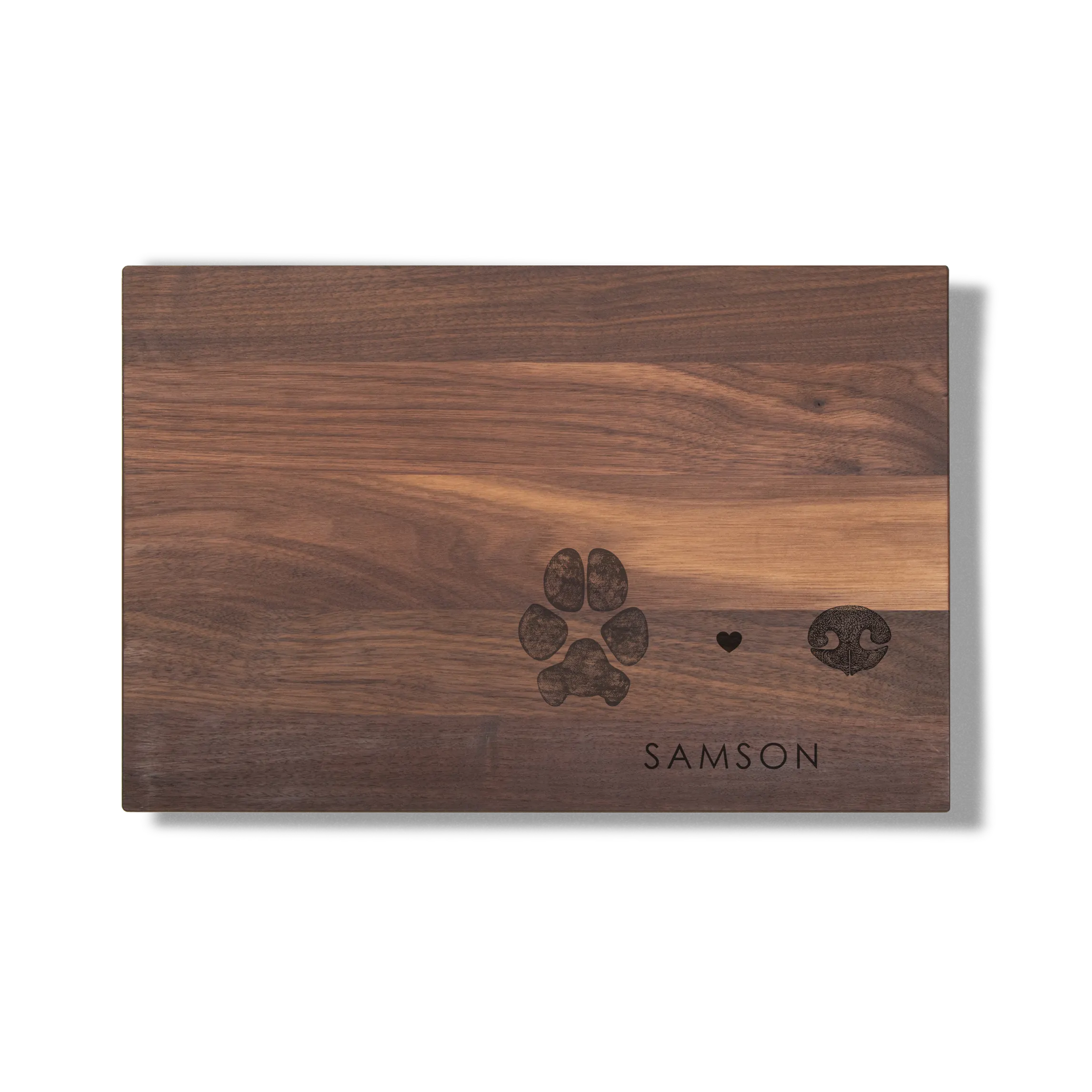 Wooden cutting board with a dark paw print, heart, and nose design engraved above the word 