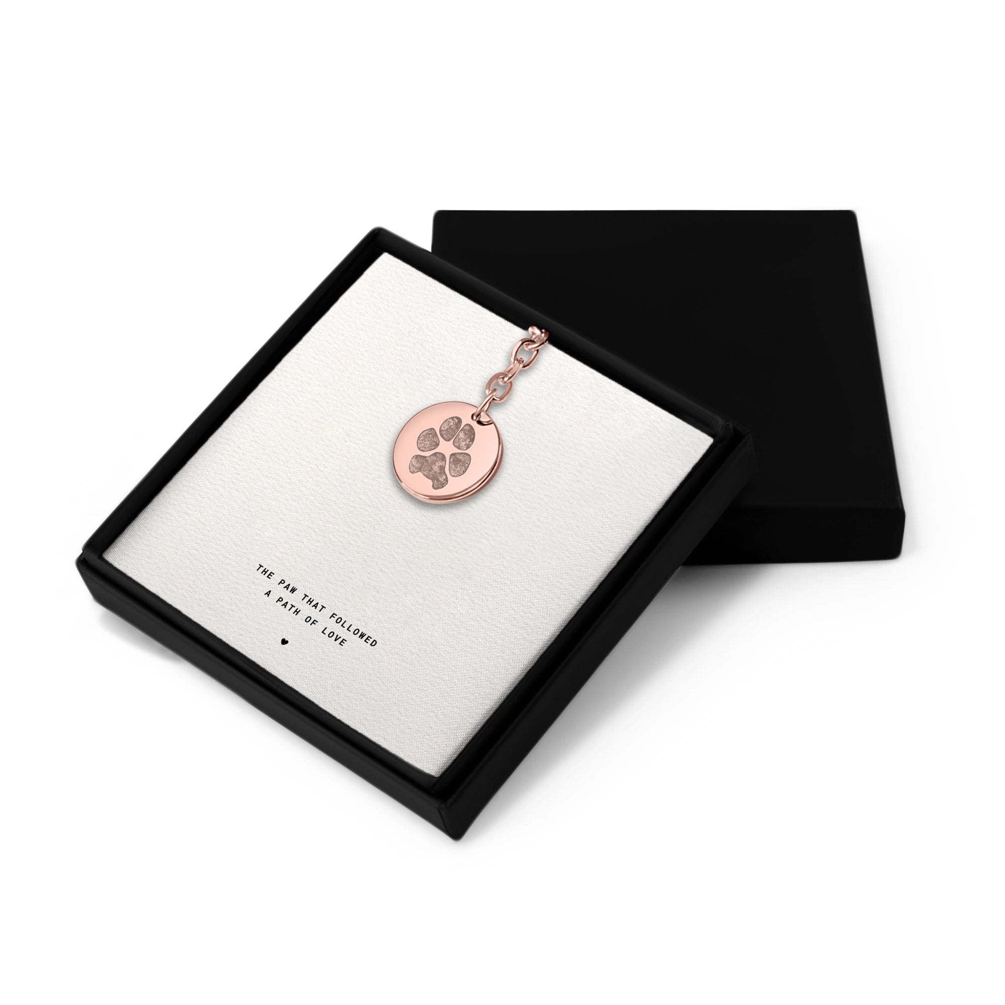 Gold keychain with a round coin pendant featuring an engraved paws printing. The simple, elegant design conveys warmth and affection, ideal for pet memorial gift.