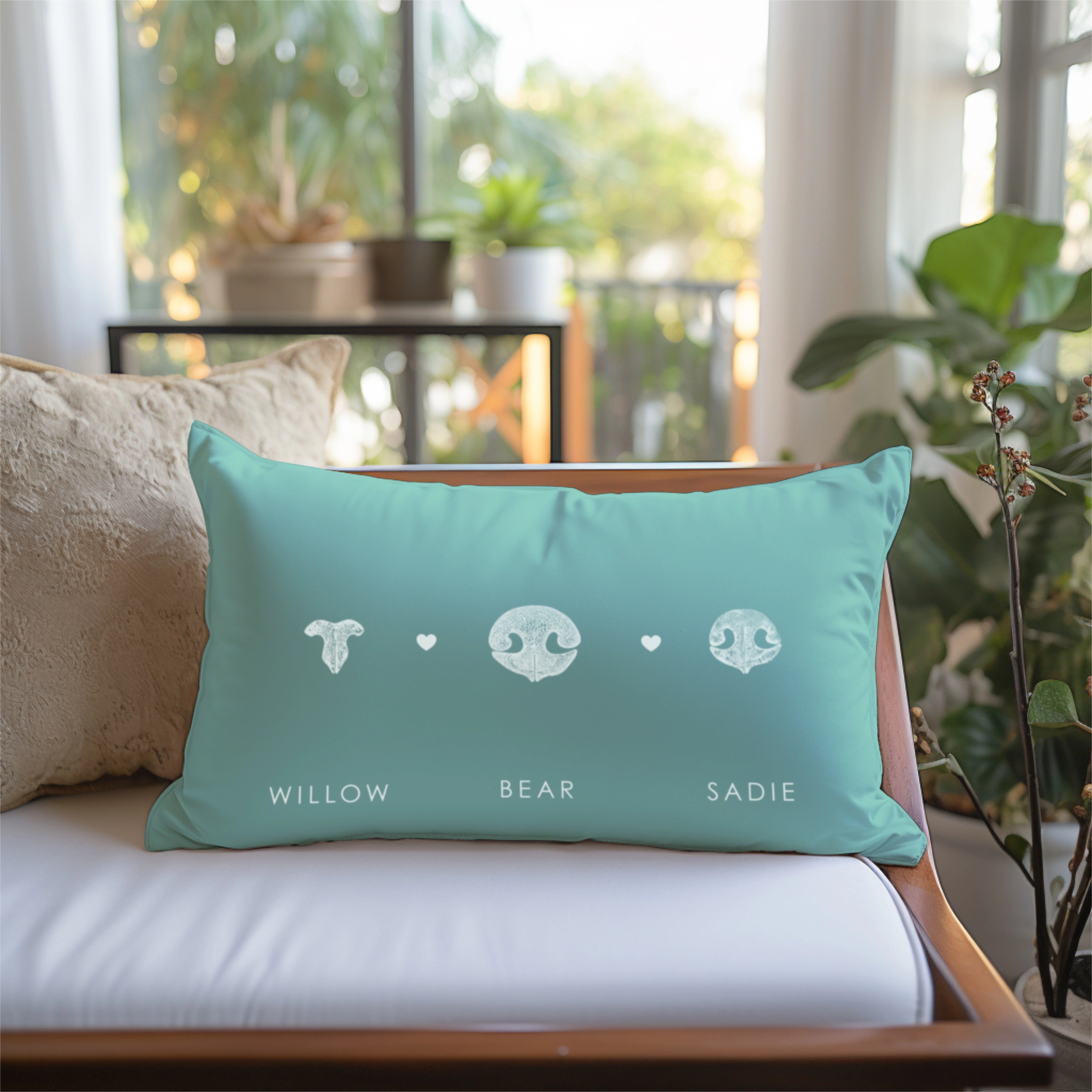 A teal pillow with three animal nose prints and names 