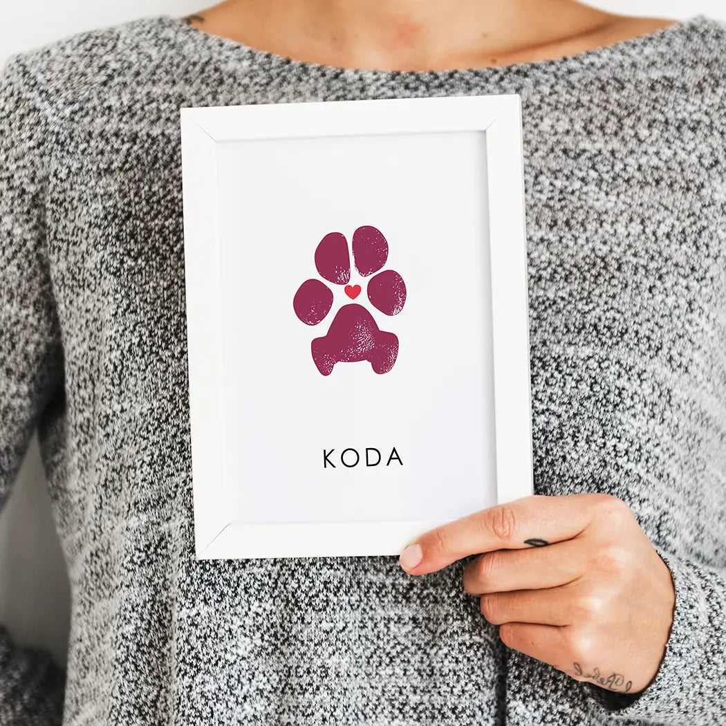 woman holding white picture frame with personalized dog paw print