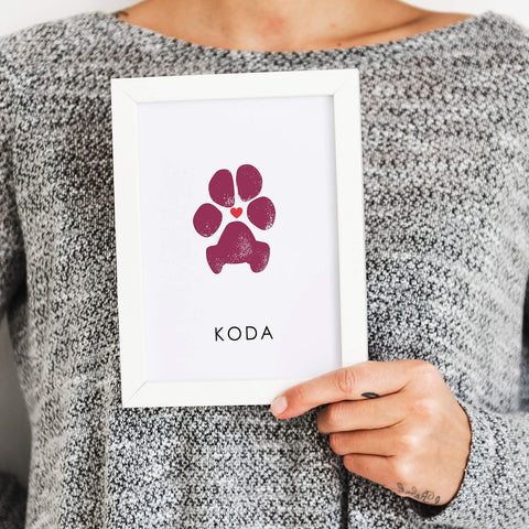 woman holding white picture frame with personalized dog paw print