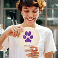 woman holding round wooden sign keepsake with dog paw print impression in purple 