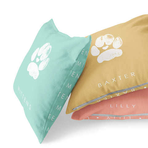 Stack of pastel colored pillows with pet paw prints and cats name