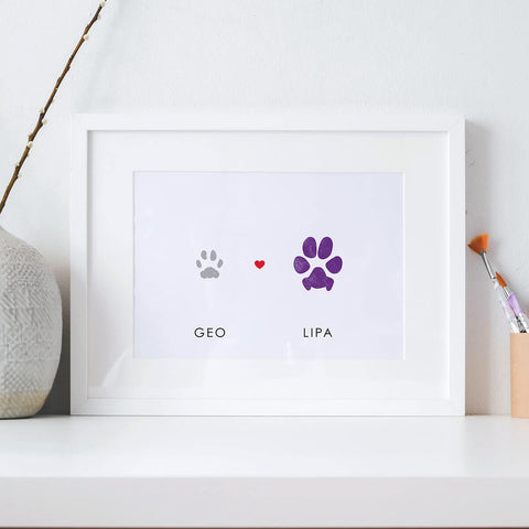 Multiple pet paw print art in white frame with grey cat paw and purple dog paw