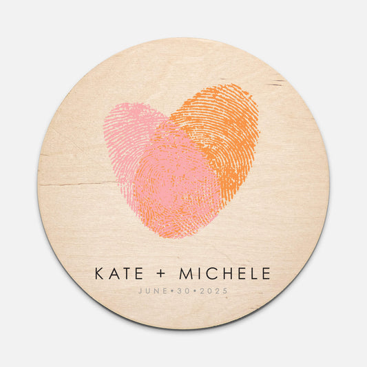 round wooden sign with pink and oragne fingerprint heart and couples names with wedding date