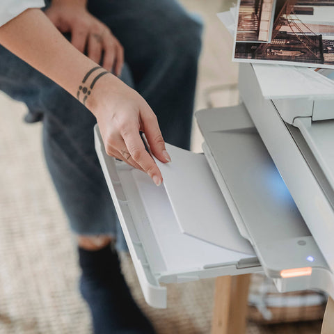 woman loading paper to print digital paw print file at home