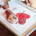woman signing wedding guest book print with couple's red fingerprint heart
