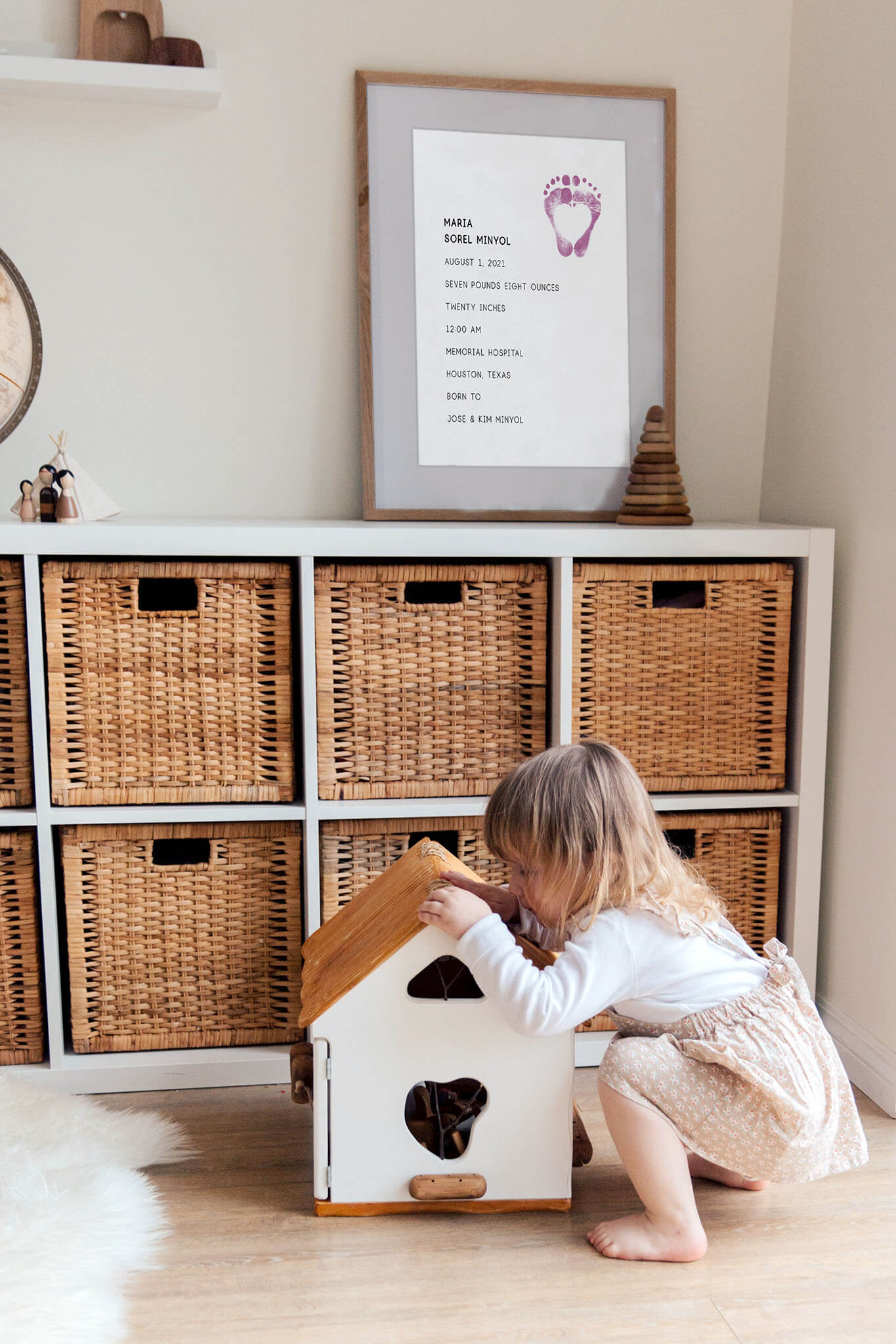 Girl in play room with custom baby footprint stats print on shelf clicking this photo leads to the footprints collection